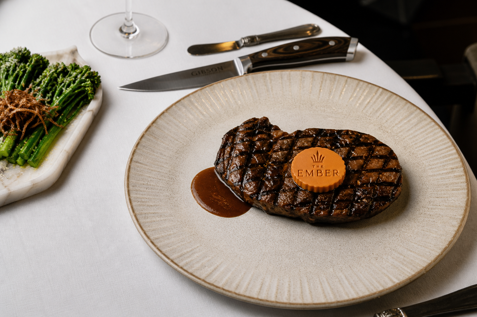 THE EMBER · Grilled steak sealed with the EMBER medallion, broccolini side